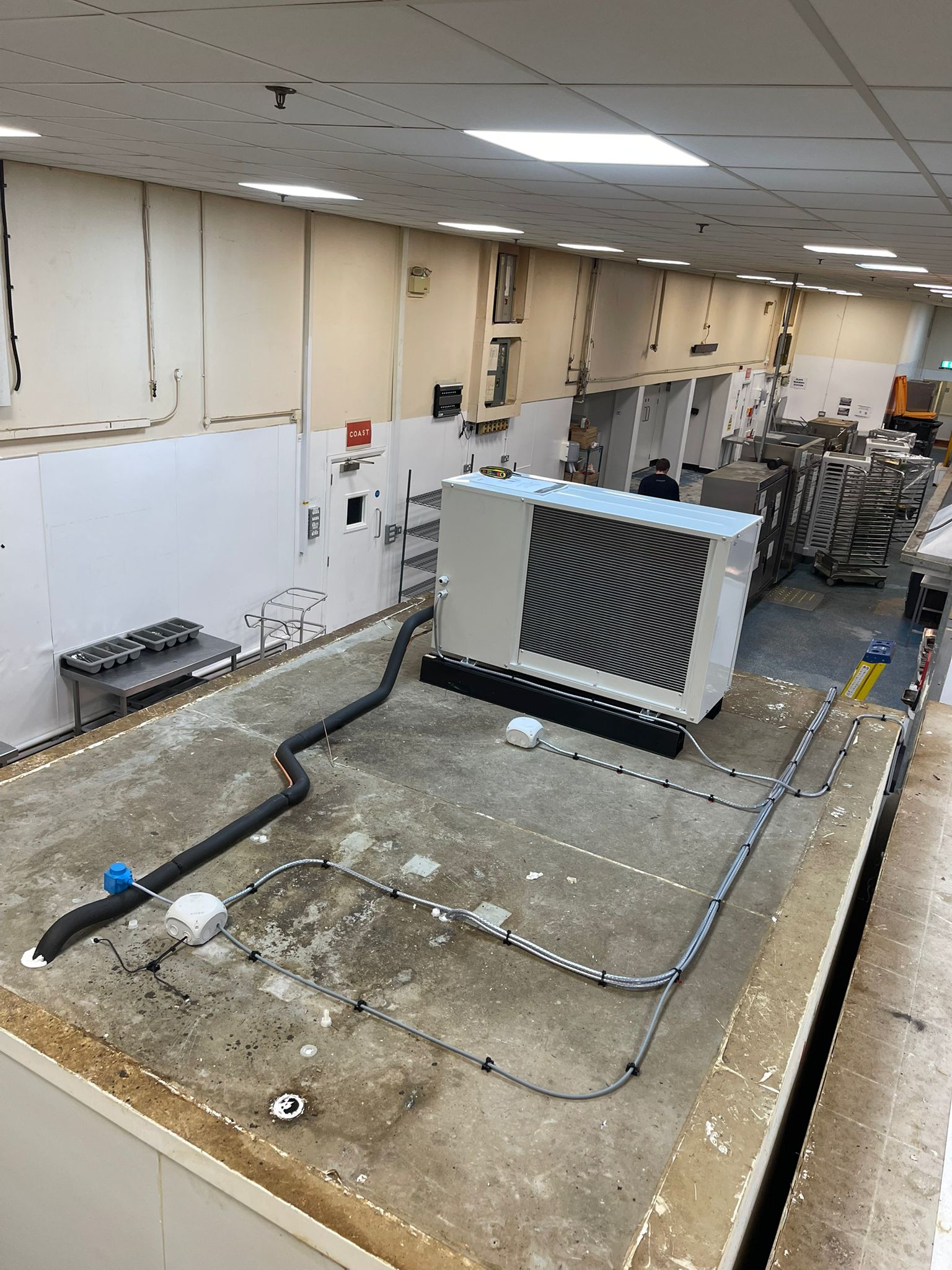 New refrigeration condenser unit installation with pipework routing in a commercial kitchen